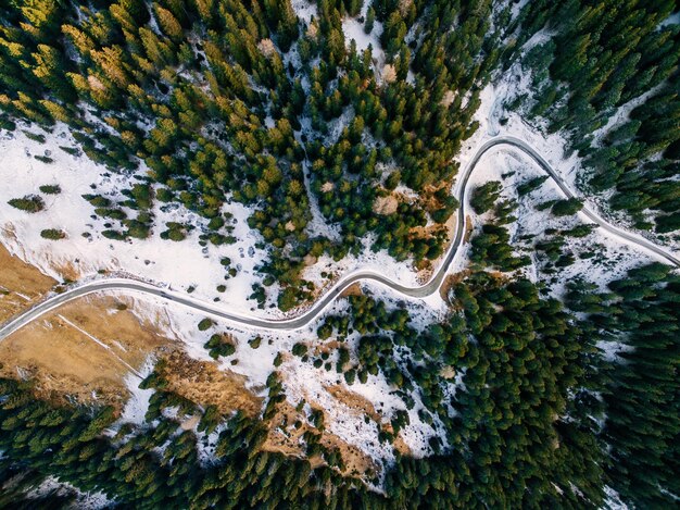 Vista aérea del bosque nevado con un camino Capturado desde arriba con un dron Dolomitas Italia