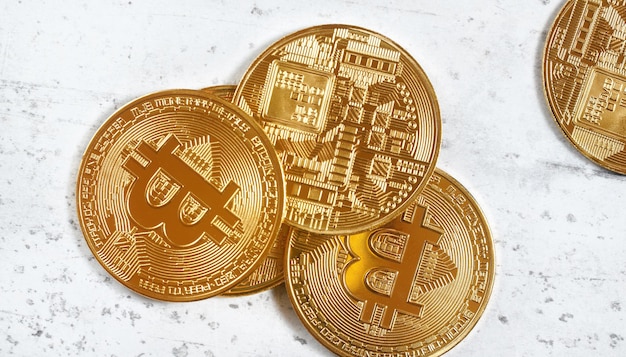 Vista aérea, btc conmemorativo dorado - criptomoneda bitcoin - monedas esparcidas en tablero de piedra blanca, detalle de cierre.