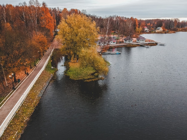 Vista aérea caminando camino a lo largo del lago, bosque colorido del otoño. San Petersburgo, Rusia.