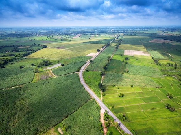 Vista aérea de un camino rural en medio de campos con un coche blanco