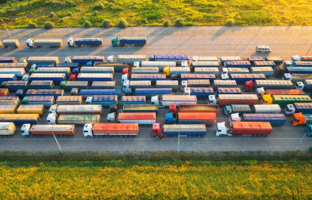 Foto vista aérea de camiones coloridos en la terminal al atardecer en verano vista superior del centro logístico industria pesada transporte transporte de carga envío camiones internacionales vista desde un dron de un camión