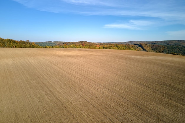 Vista aérea del campo agrícola arado con suelo fértil cultivado preparado para plantar cultivos en primavera