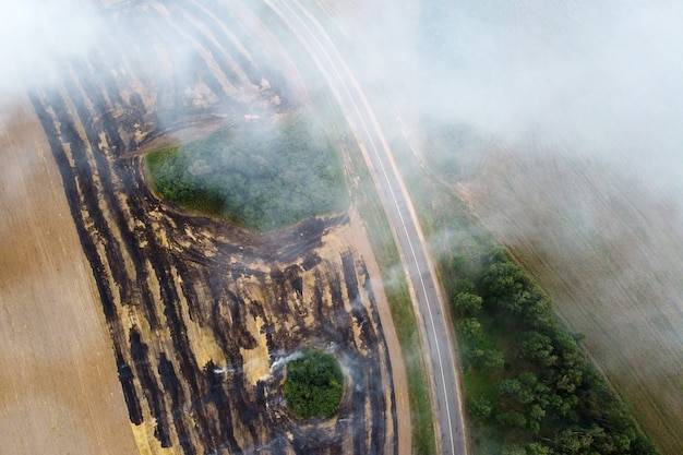 Vista aérea del campo en llamas con humo en tierras agrícolas