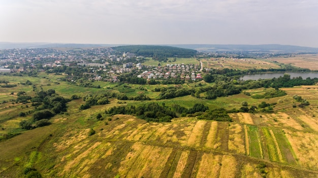 Vista aérea del campo de verano. Un vuelo sobre un campo verde y una ciudad.