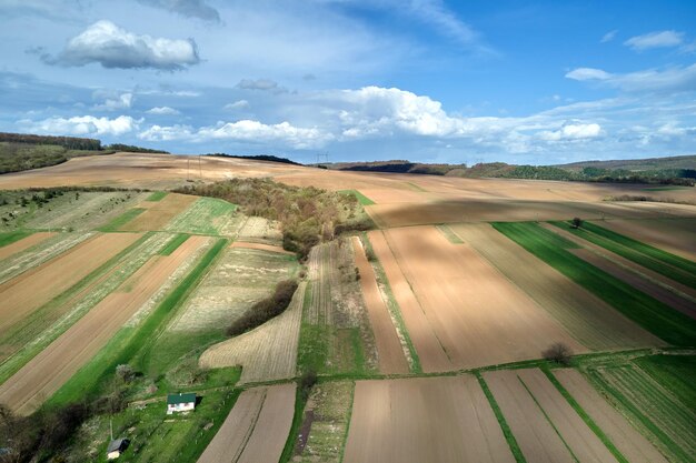 Vista aérea de campos agrícolas arados con suelo fértil cultivado preparado para plantar cultivos entre bosques verdes en primavera