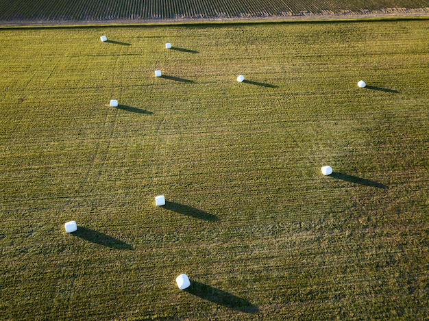 Vista aérea de los campos agrícolas con fardos de heno durante un atardecer de verano