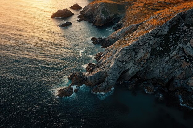 Una vista aérea captura la belleza escarpada de una costa rocosa mientras el sol se pone sobre el horizonte La luz del anochecer proyecta sombras en el mar y las costas rocosas desde arriba Generado por IA