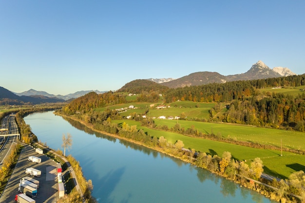 Vista aérea de la carretera interestatal con tráfico rápido cerca del gran río en las montañas de los Alpes