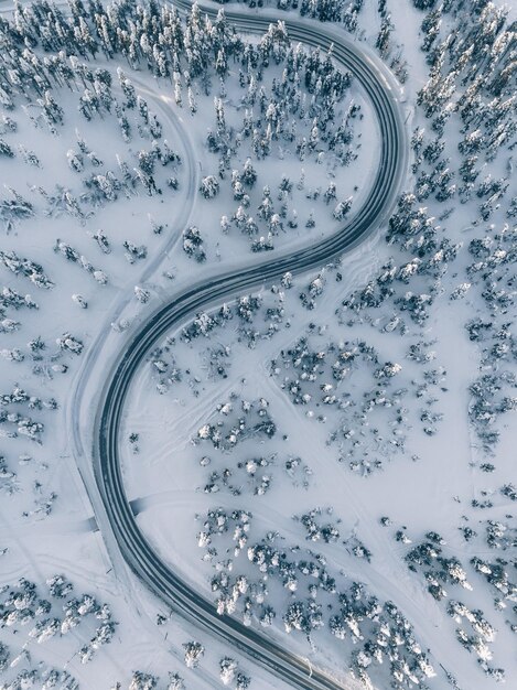 Vista aérea de la carretera de invierno en el bosque cubierto de nieve a vista de pájaro Finlandia Laponia