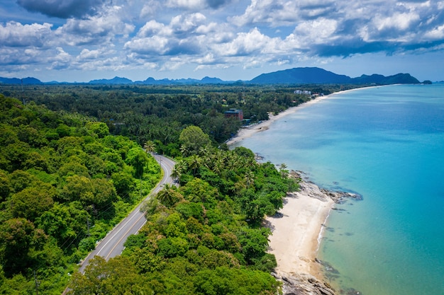 Vista aérea de la carretera entre la palmera de coco y el gran océano durante el día en Nakhon Si Thammarat, Tailandia