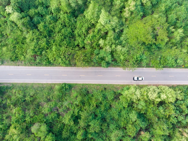 Vista aérea de la carretera pasando por el bosque con un automóvil pasando por