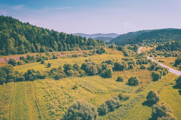 Vista aérea de la carretera rural y campos cultivados en las colinas en un soleado día de primavera