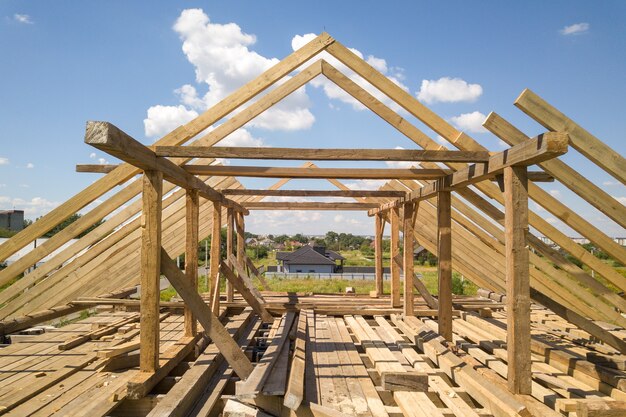 Vista aérea de la casa sin terminar con estructura de techo de madera en construcción.