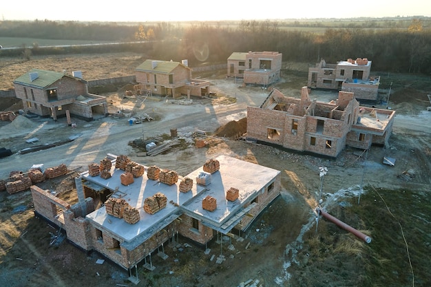 Vista aérea de casas nuevas con paredes de ladrillo en construcción en el área suburbana rural Desarrollo de bienes raíces en los suburbios de la ciudad moderna