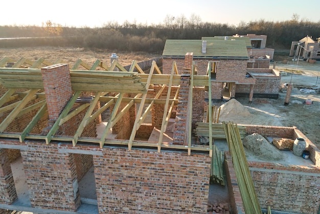 Vista aérea de casas nuevas con paredes de ladrillo en construcción en el área suburbana rural Desarrollo de bienes raíces en los suburbios de la ciudad moderna