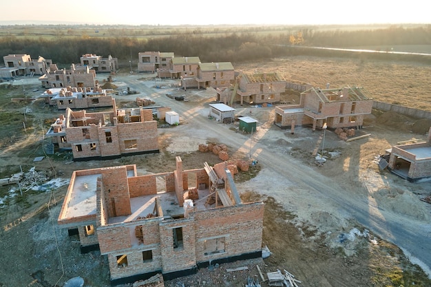 Vista aérea de casas nuevas con paredes de ladrillo en construcción en el área suburbana rural Desarrollo de bienes raíces en los suburbios de la ciudad moderna