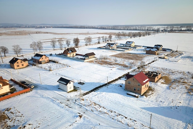 Vista aérea de casas privadas con techos cubiertos de nieve en el área rural de los suburbios en invierno frío