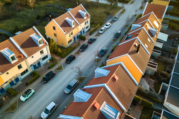 Vista aérea de casas residenciales con techos rojos y calles con automóviles estacionados en la zona rural de la ciudad. Suburbios tranquilos de una ciudad europea moderna.