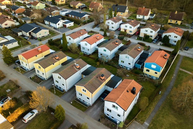 Foto vista aérea de casas residenciales con techos rojos y calles con automóviles estacionados en la zona rural de la ciudad.