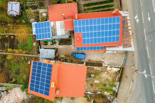 Vista aérea de casas residenciales con tejados cubiertos con paneles solares fotovoltaicos en zona rural suburbana