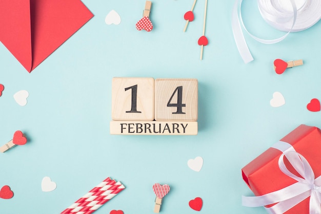 Vista aérea de cerca la foto del 14 de febrero en el calendario de forma de cubo de madera y accesorios del día de San Valentín alrededor