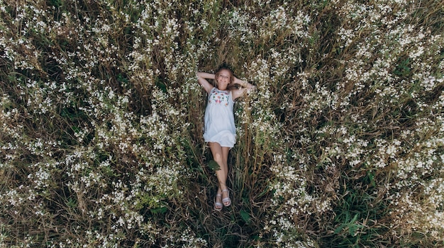 Vista aérea de una chica de belleza acostada en un campo de flores y relajante