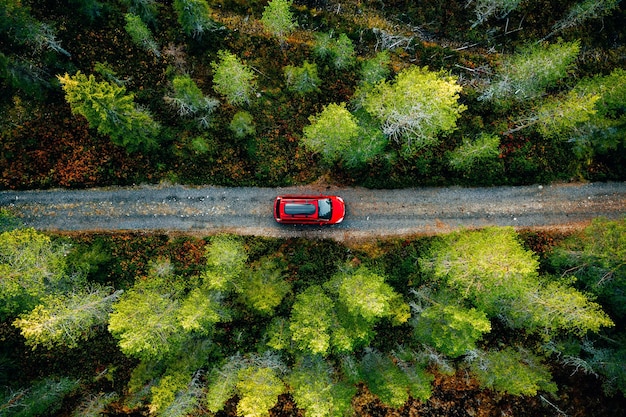 Foto vista aérea del coche rojo para viajar con un portaequipajes en una carretera rural en finlandia