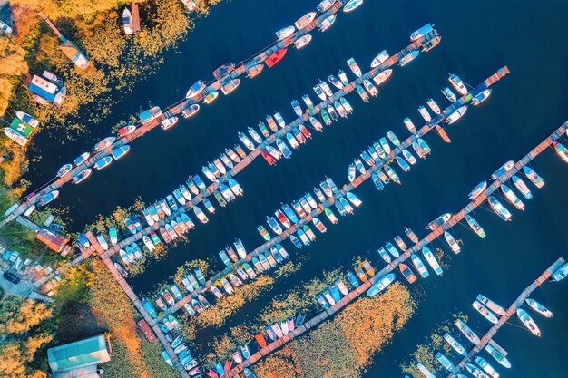Foto vista aérea de coloridos barcos y yates en el mar al atardecer en verano. paisaje con muelle, lanchas y veleros, nenúfares amarillos, lago con agua azul. vista superior del puerto. transporte