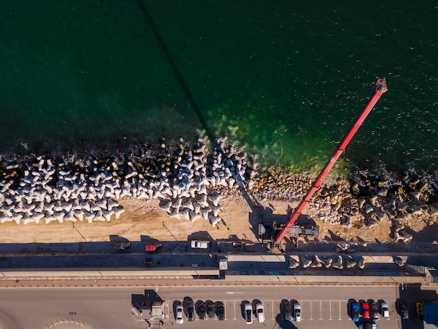 Vista aérea de la construcción del rompeolas Bulldozer y grúa sobre un montón de rocas en el mar