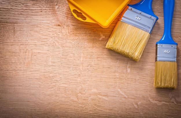 Vista aérea de copyspace organizado dos pinceles con asas azules y lata de pintura amarilla en concepto de construcción de tablero de madera