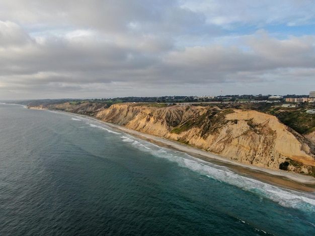 Vista aérea de la costa del Pacífico con acantilados de arenisca amarilla y olas corriendo por la playa