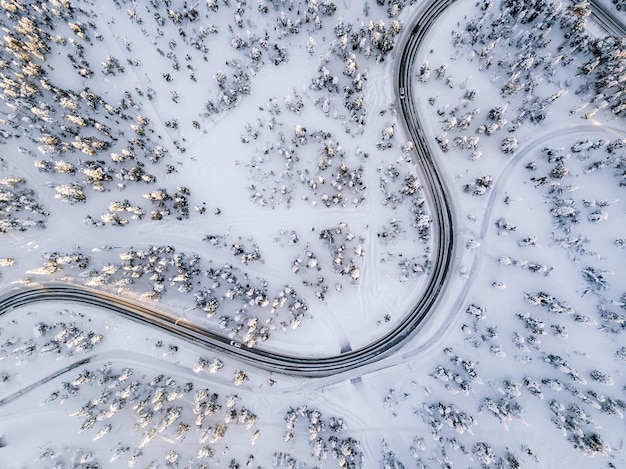 Vista aérea de Curvy Windy Road en un bosque cubierto de nieve en invierno Finlandia Laponia vista superior