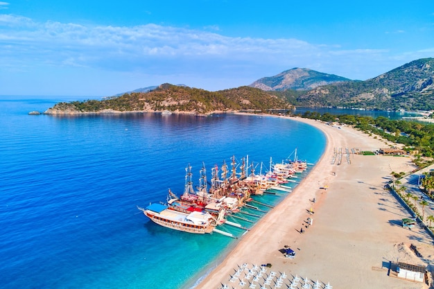 Vista aérea da baía do mar mediterrâneo com praia de areia de montanha e barcos em dia ensolarado no verão Drone foto da lagoa azul em Oludeniz Turquia