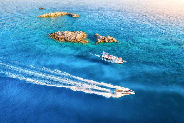 Vista aérea da bela lancha no mar ao pôr do sol nas férias de verão na Turquia Vista superior do drone do barco de iate de luxo água azul clara rochas pedras Viagens Natureza Paisagem tropical