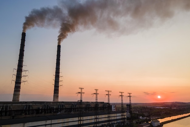 Vista aérea da central de energia a carvão, tubos altos com fumaça preta se movendo para cima poluindo a atmosfera ao pôr do sol Produção de energia elétrica com conceito de combustível fóssil