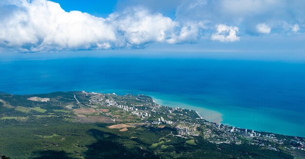 Vista aérea da cidade, colinas e florestas perto da vila costeira e do mar azul