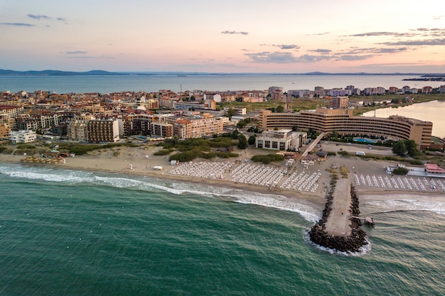 Vista aérea da cidade de Pomorie, localizada na costa do mar Negro. Vista superior das praias de areia com muitos edifícios de hotéis e infraestrutura turística.