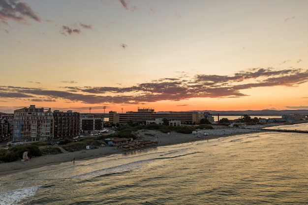 Vista aérea da cidade de Pomorie, localizada na costa do mar Negro. Vista superior das praias de areia com muitos edifícios de hotéis e infraestrutura turística.