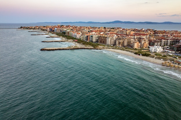 Vista aérea da cidade de Pomorie, localizada na costa do mar Negro. Vista superior das praias de areia com muitos edifícios de hotéis e infraestrutura turística.