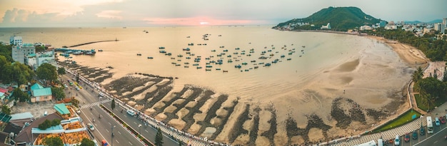 Vista aérea da cidade de Vung Tau com belo pôr do sol e tantos barcos Vista panorâmica costeira de Vung Tau de cima com ondas do litoral ruas coqueiros e montanha Tao Phung no Vietnã