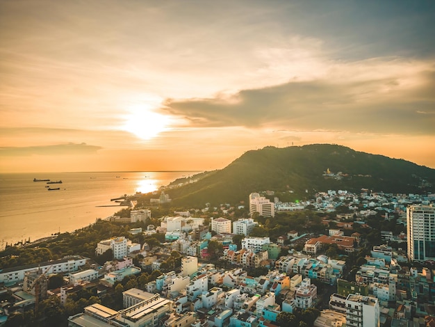 Vista aérea da cidade de Vung Tau com belo pôr do sol e tantos barcos Vista panorâmica costeira de Vung Tau de cima com ondas do litoral ruas coqueiros e montanha Tao Phung no Vietnã