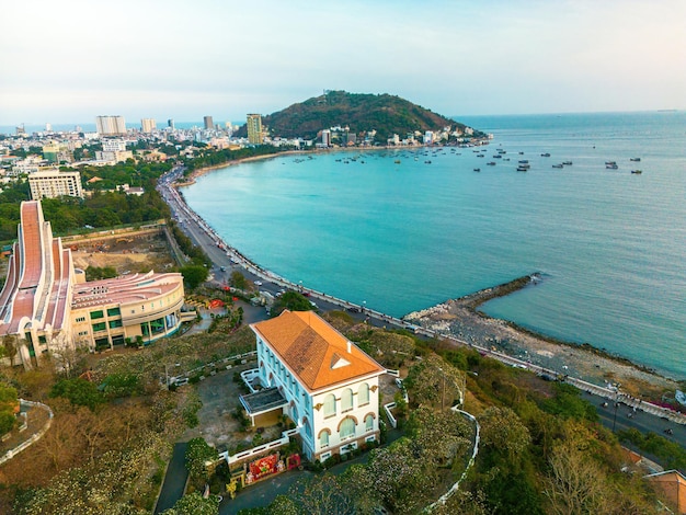 Vista aérea da cidade de Vung Tau com belo pôr do sol Palácio de Bach Dinh Vista panorâmica da costa de Vung Tau de cima com ondas, ruas costeiras, coqueiros e montanha Tao Phung no Vietnã