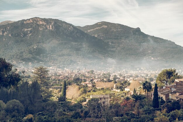 Vista aérea da cidade velha localizada perto do cume da montanha em dia nublado na zona rural verde de Maiorca