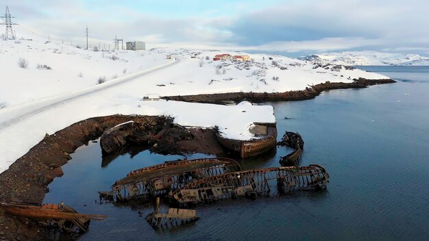 Foto vista aérea da costa marítima nevada do inverno com barcos arruinados após a filmagem do naufrágio antigo afundado