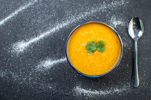 Vista aérea da deliciosa sopa de lentilha vermelha em uma tigela servida com verduras e colher no lado esquerdo em fundo branco preto com espaço livre