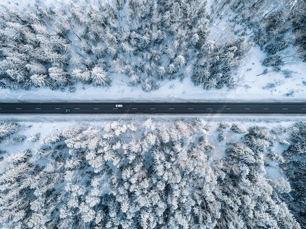 Vista aérea da estrada de inverno e floresta com árvores cobertas de neve na vista superior da Finlândia