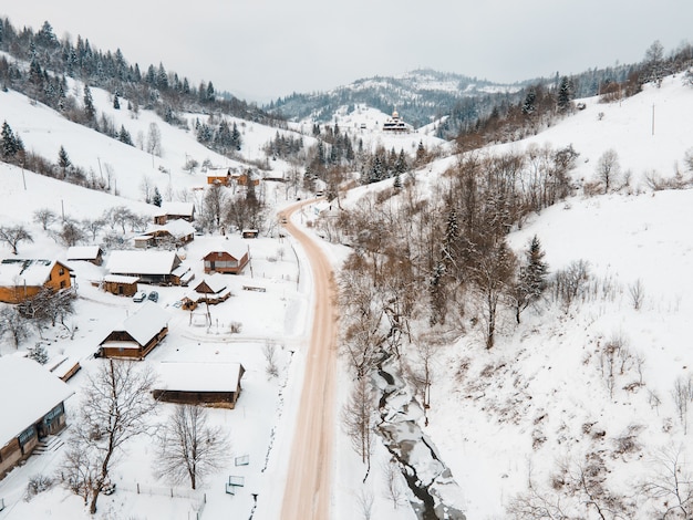 Vista aérea da estrada em uma vila coberta de neve no meio das montanhas dos Cárpatos, na Ucrânia