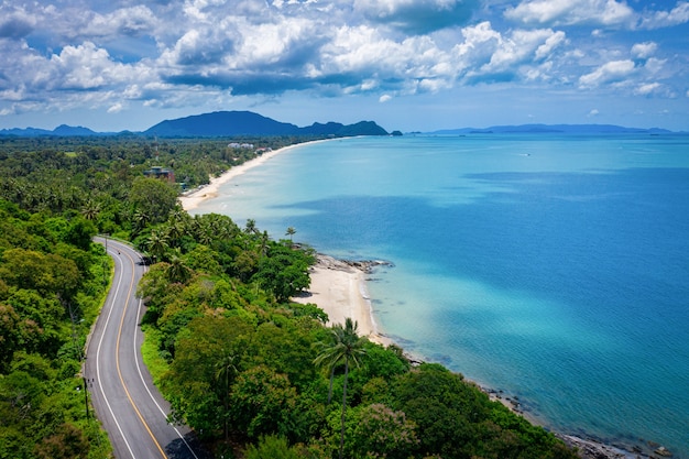 Vista aérea da estrada entre a palmeira de coco e o grande oceano durante o dia em Nakhon Si Thammarat, Tailândia