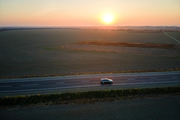Vista aérea da estrada intermunicipal com carro turva rápido ao pôr do sol. Vista superior do drone do tráfego da rodovia à noite.