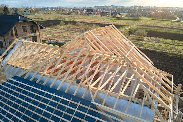 Vista aérea da estrutura inacabada de uma casa particular com paredes de concreto leve aerado e estrutura do telhado de madeira em construção.